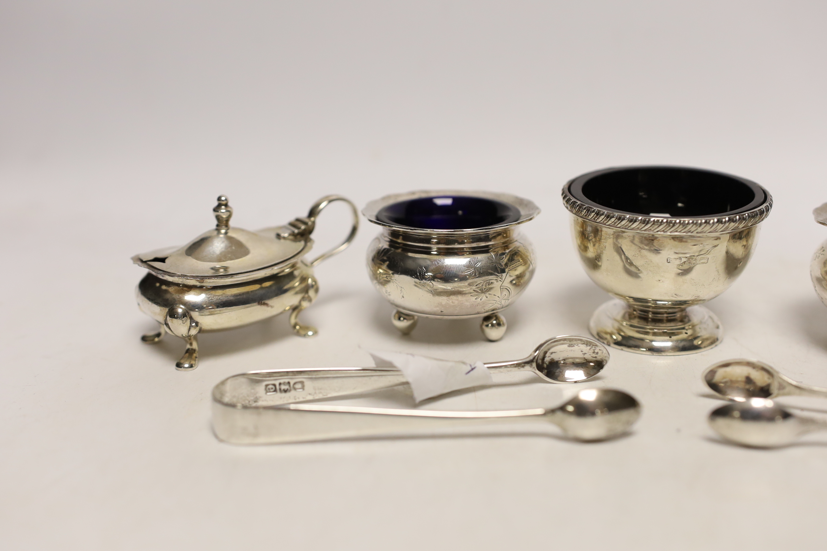 A pair of silver mustard pots, a pair of silver salts, one other silver salt, and two pairs of sugar tongs.